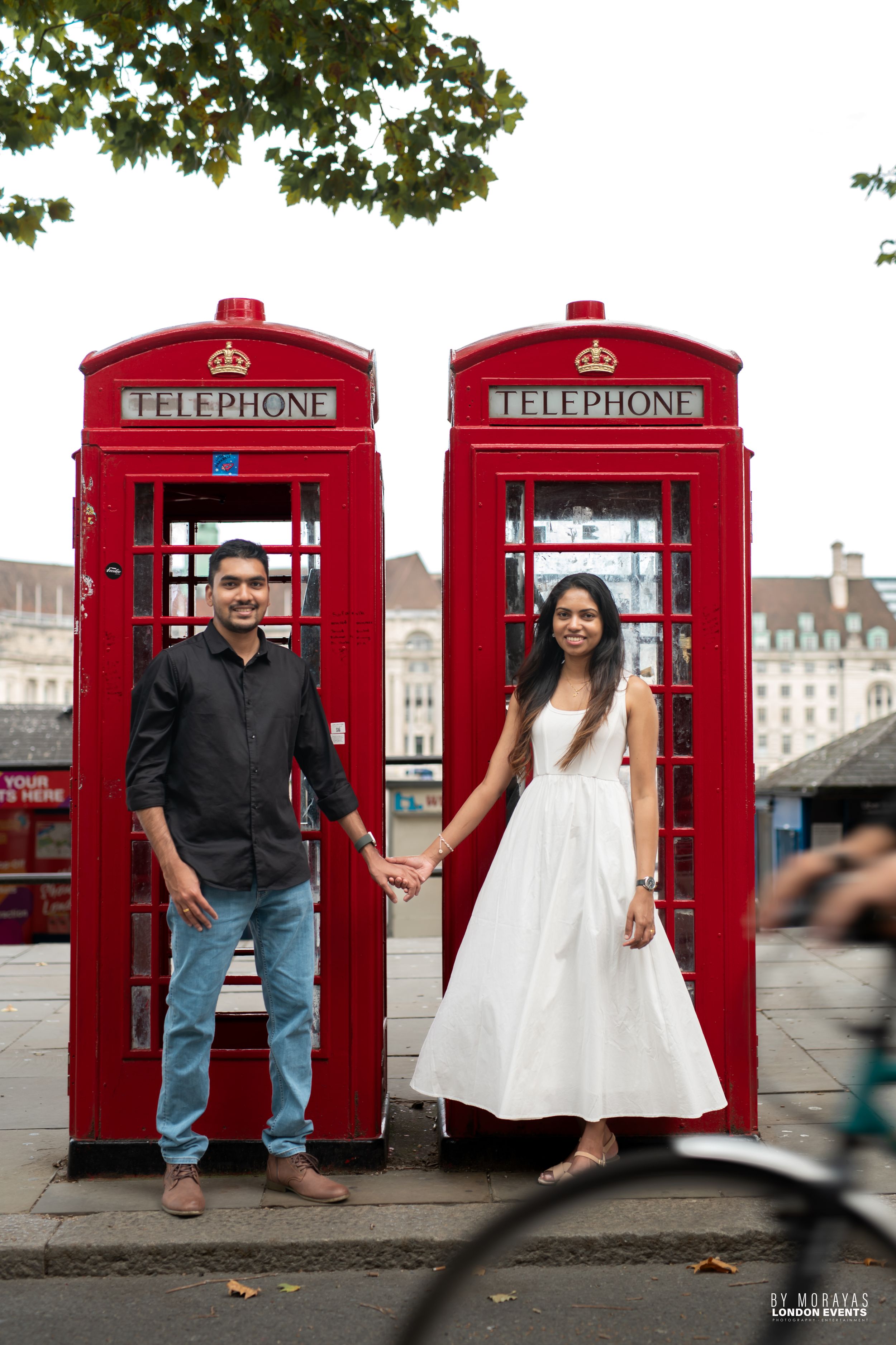 A couple poses playfully in London's iconic red telephone booths.
