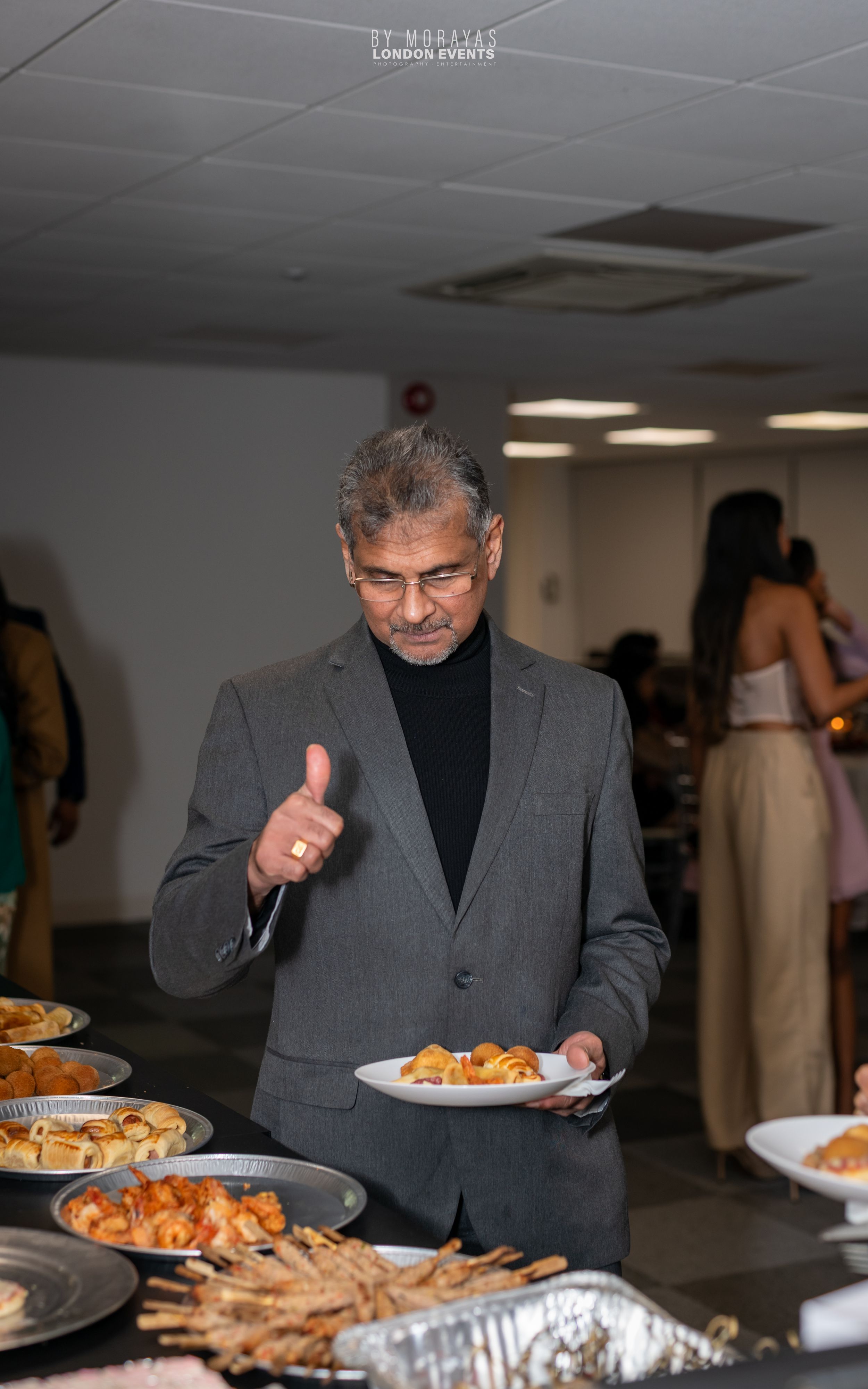 Guest selecting food from an elegant wedding reception buffet spread.