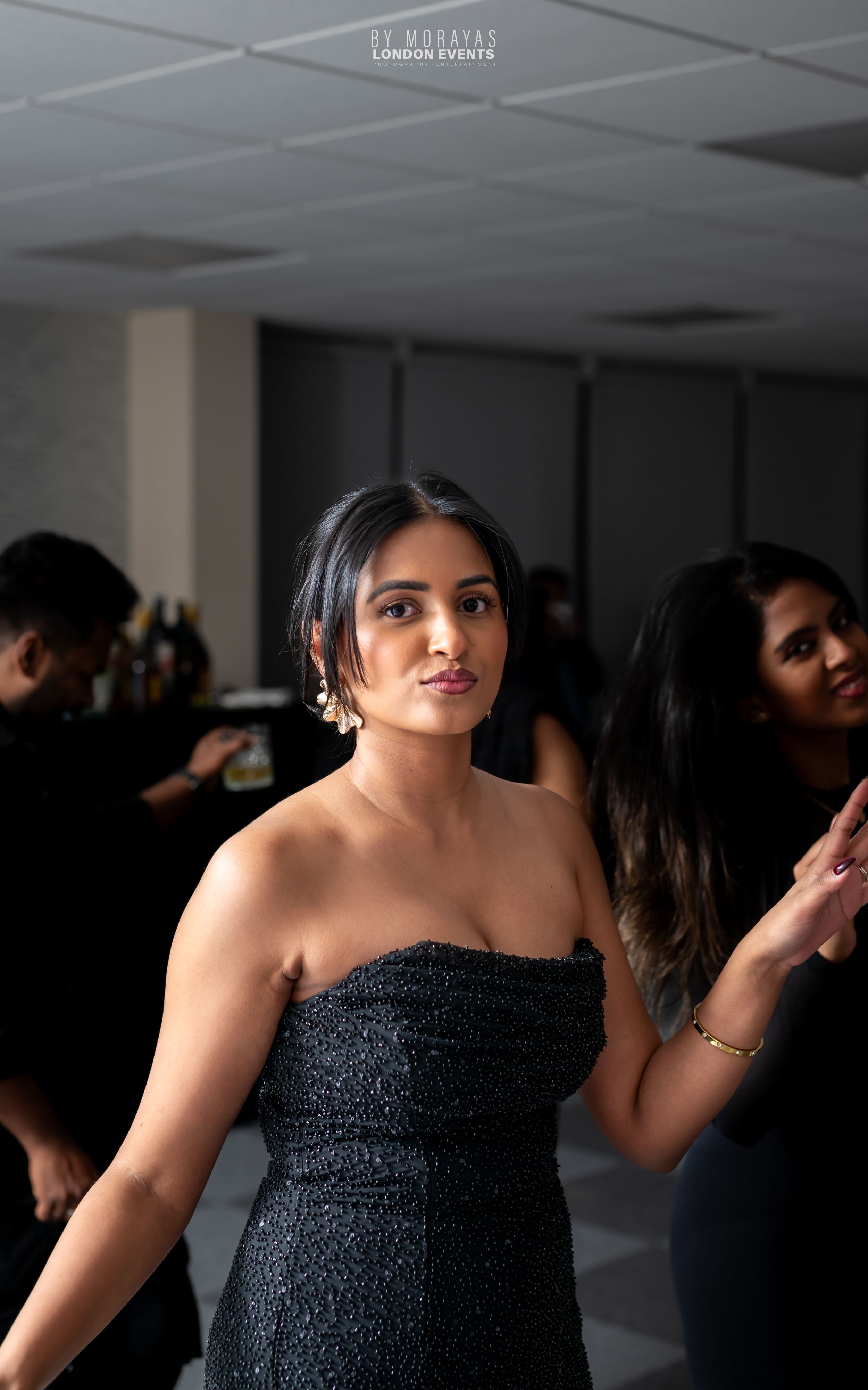 Party scene with guests in formal attire dancing in a dimly lit room.