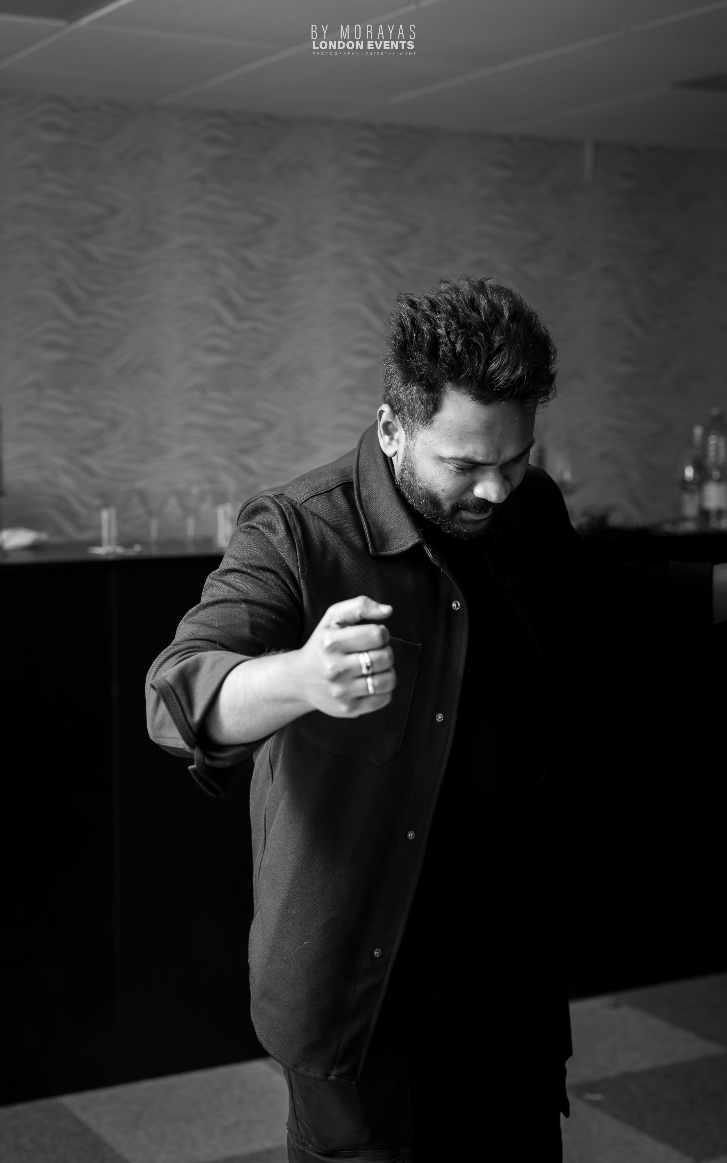 Dramatic black and white portrait of person in dark clothing against moody lighting.