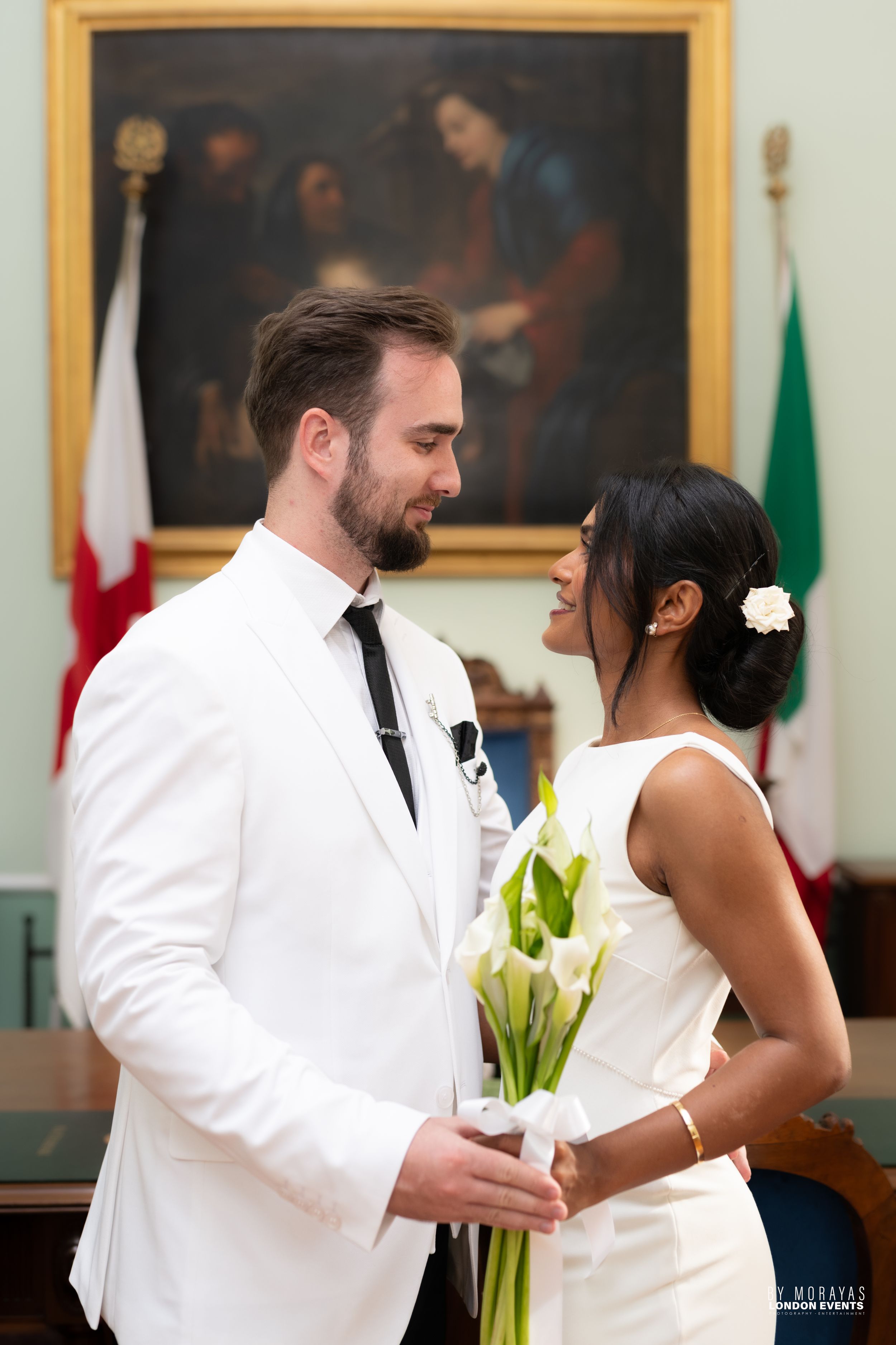 Wedding couple sharing a dance in an elegant room with flags and artwork.