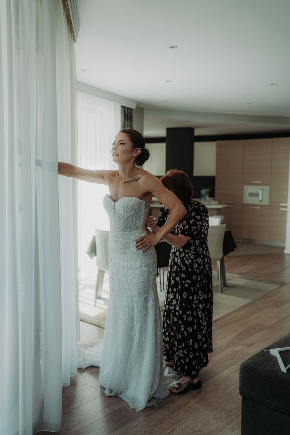 Getting ready scene in a bright modern room with light wood floors and white curtains.