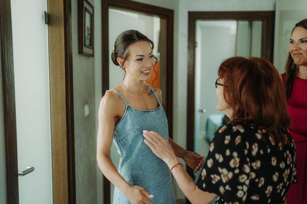 Wedding preparations in a bright white room with bridesmaids in blue dresses.