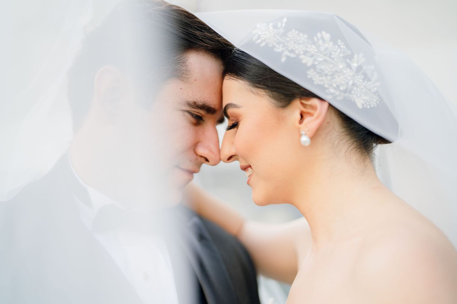Romantic close-up wedding portrait with delicate lace veil details.