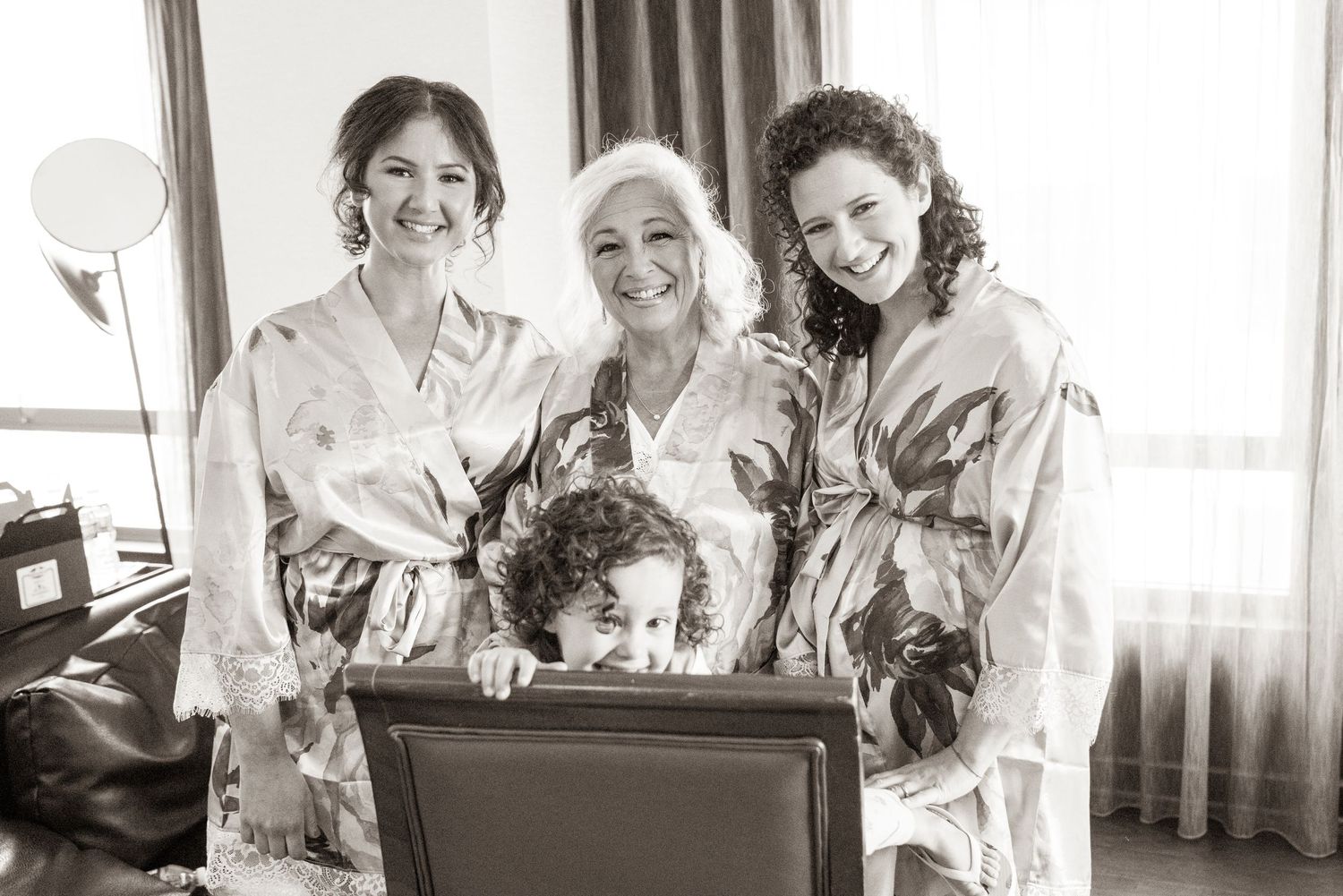 Group wearing matching floral robes pose together during wedding preparations.