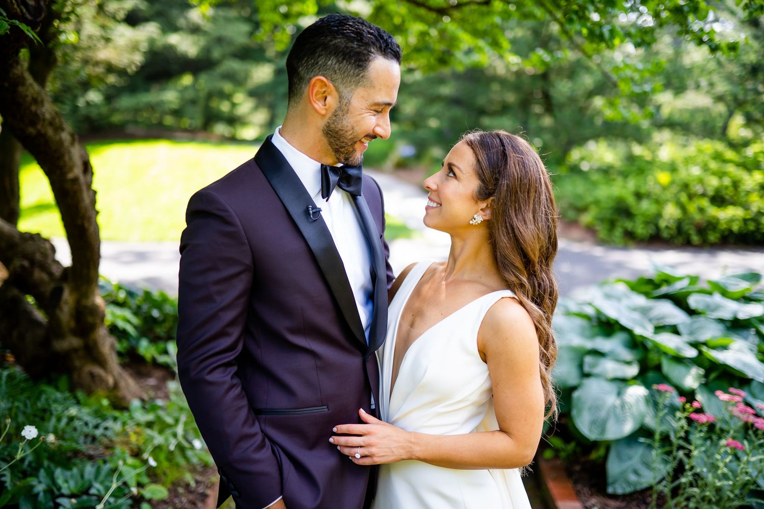 Romantic garden wedding portrait with lush greenery and elegant attire.