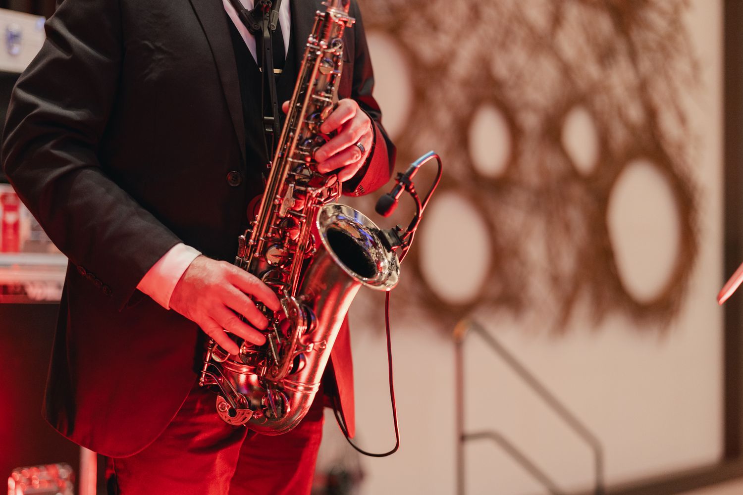 Close-up of saxophone player performing in formal attire with dramatic red lighting.