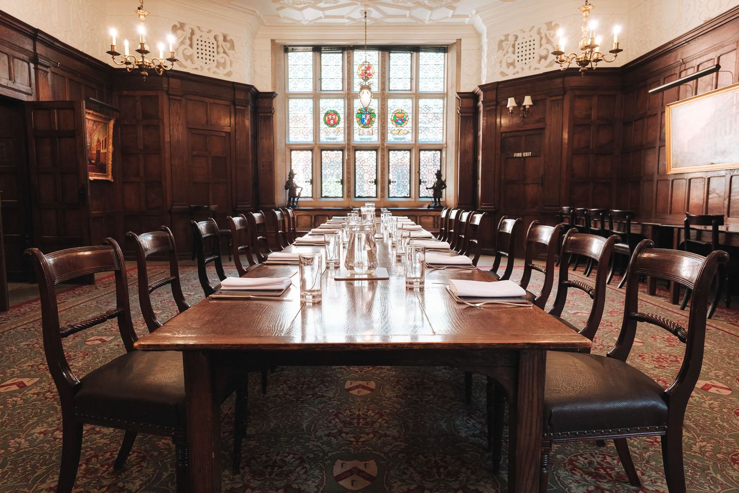 Grand hall with wooden chairs arranged in rows and ornate chandeliers hanging from a vaulted ceiling.