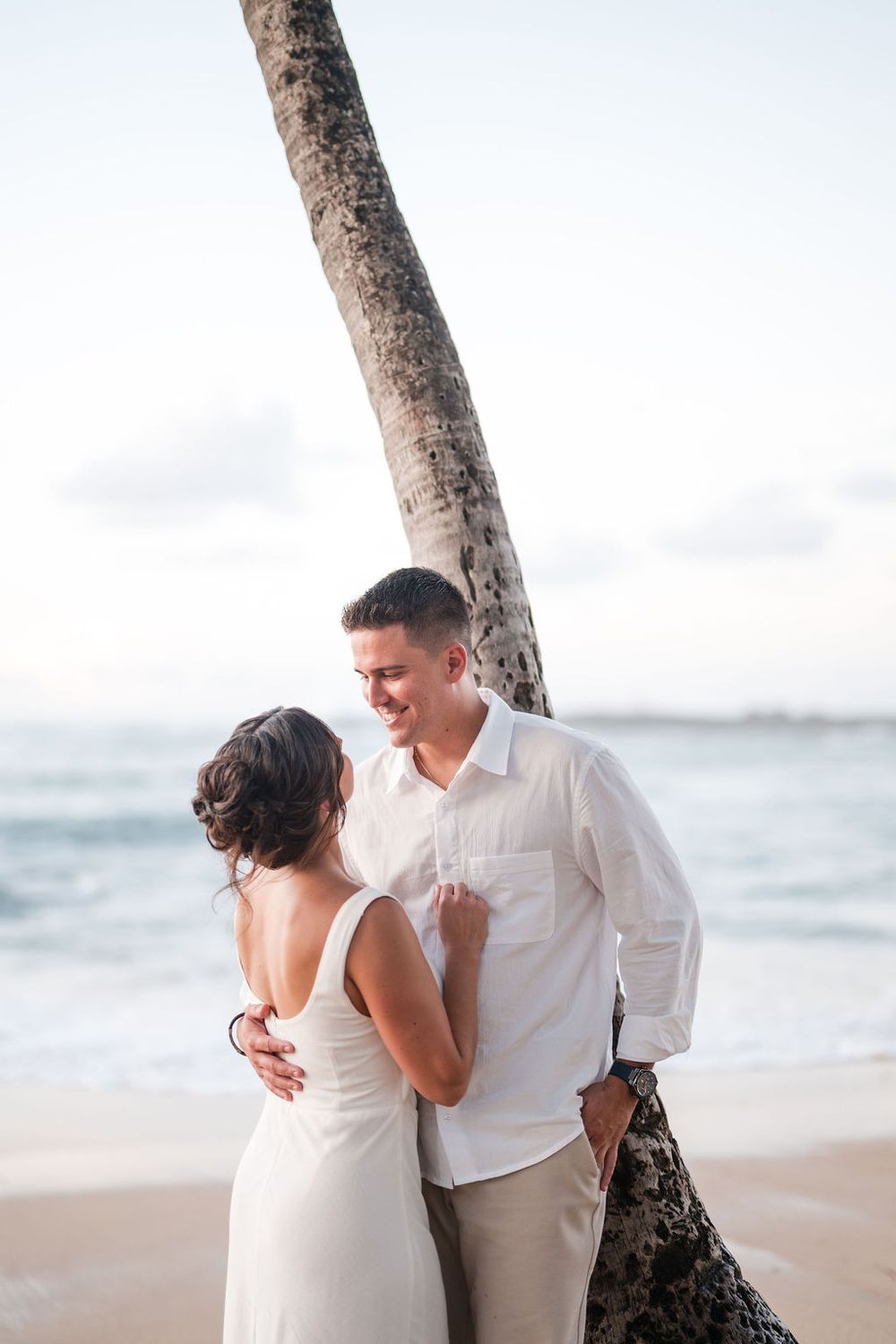 Couple embracing under palm tree during engagement photos in San Juan Puerto Rico