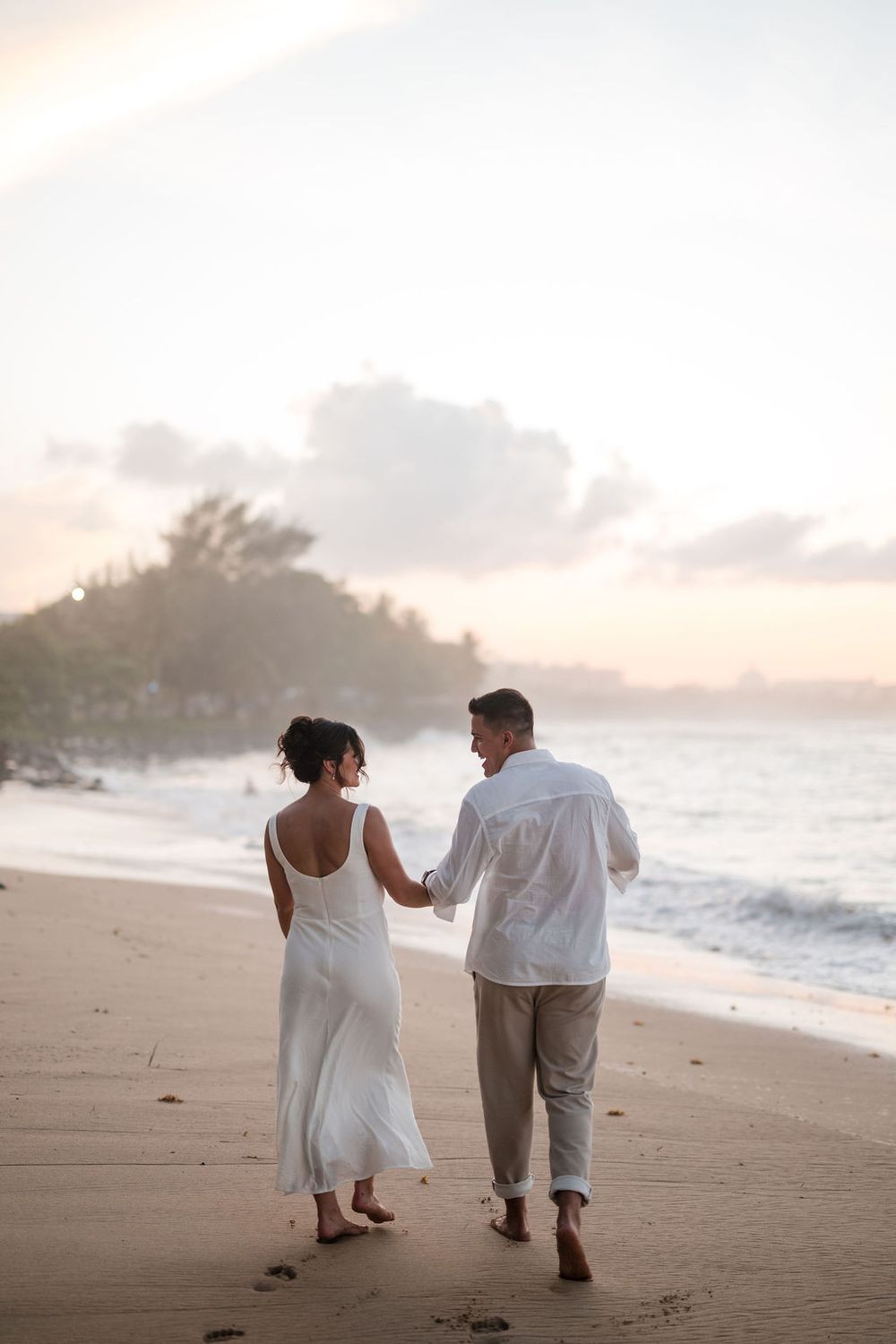 Couple walking together on beach during engagement session at El Escambrón in San Juan Puerto Rico