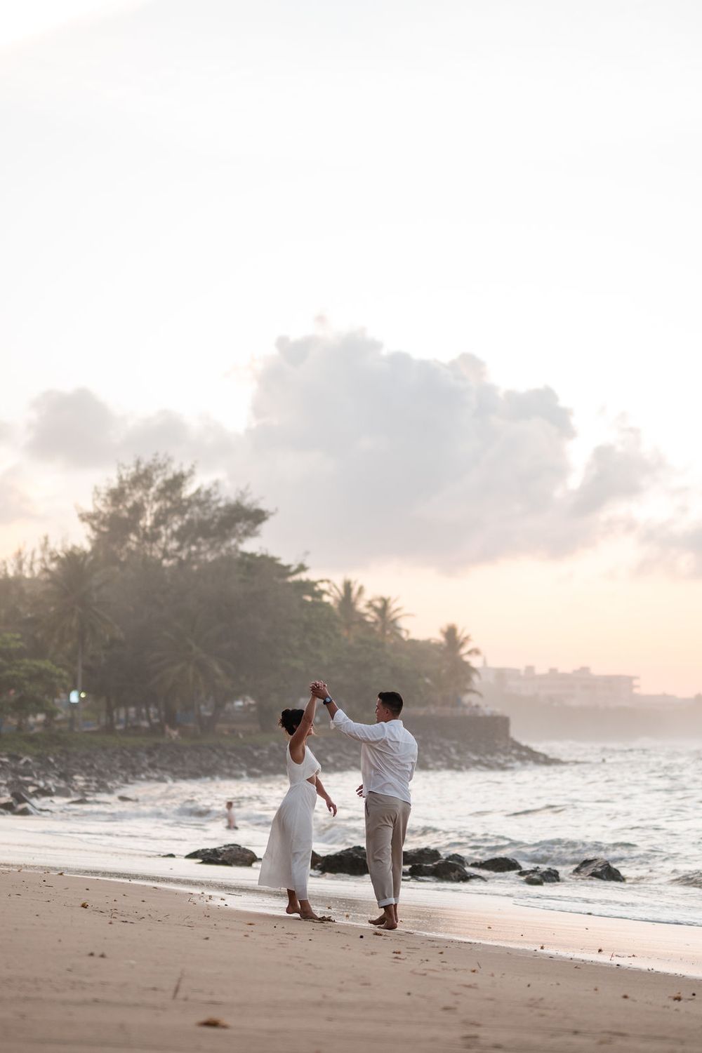Wide view of couple walking along shoreline at El Escambrón beach in Puerto Rico