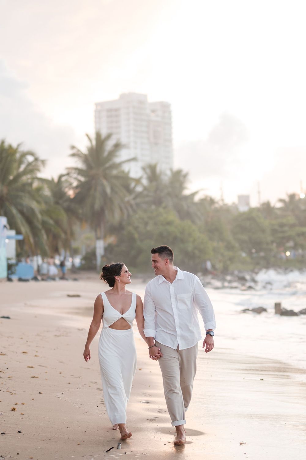 Wide view of couple walking on beach during sunset at El Escambrón Puerto Rico