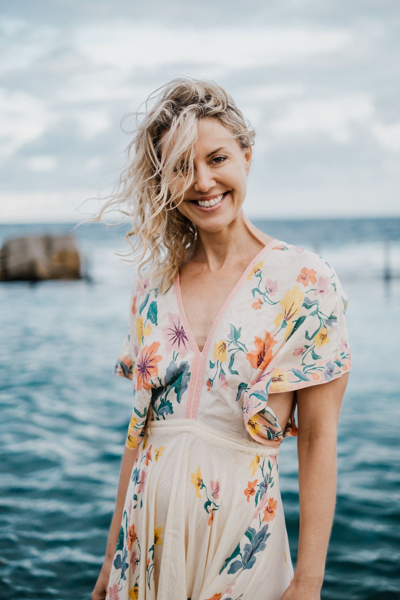 A floral summer dress stands out against the blue ocean backdrop on a cloudy day.