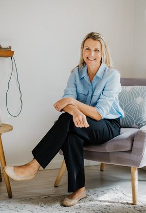Professional portrait in a modern office setting wearing a light blue button-up shirt.