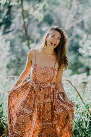 A carefree summer moment in a patterned maxi dress surrounded by sunlit foliage.