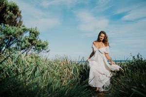 A series of lifestyle photos showing a white dress flowing in tall grass against a blue sky.