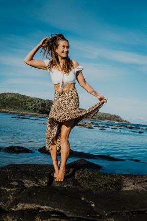 Dynamic poses on rocky coastal terrain with ocean and blue sky backdrop.