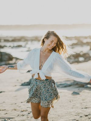 Candid beach photoshoot featuring a white top and floral skirt ensemble on sandy shores.