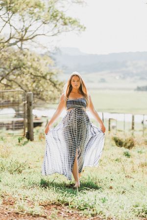 Flowing tie-dye dress movement captured in a sunny field with mountains in background.