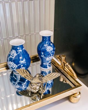 Blue and white porcelain vases displayed with gold decorative elements on a mirrored tray.