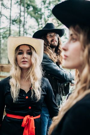 Artistic portrait series with black clothing, red sash, and contrasting light and dark hats.