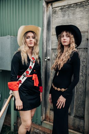 Fashion shoot featuring western-inspired black outfit with red accents and cowboy hat.