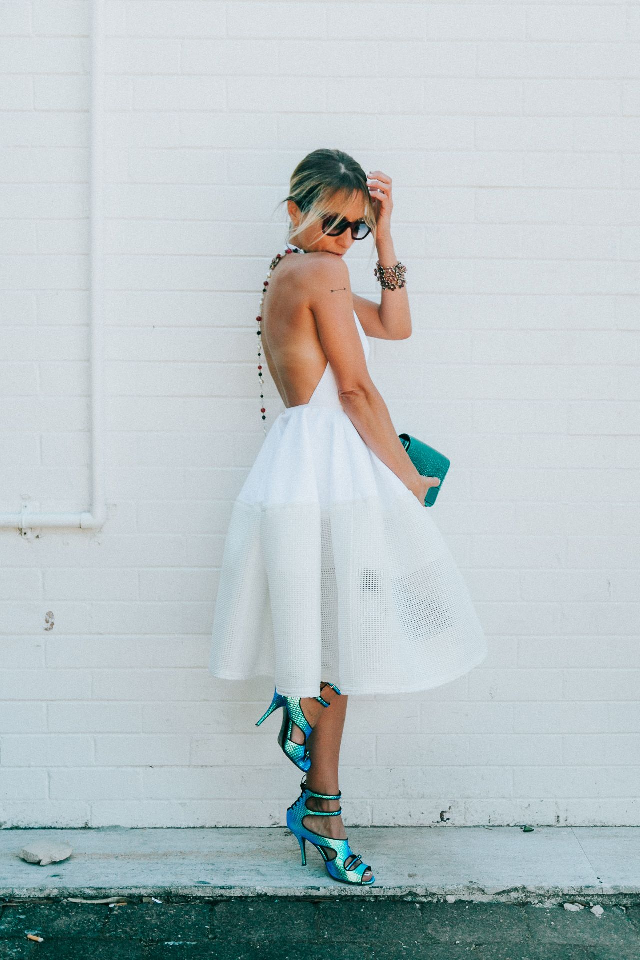 Artistic series of a white dress twirling against a white wall with teal accents.