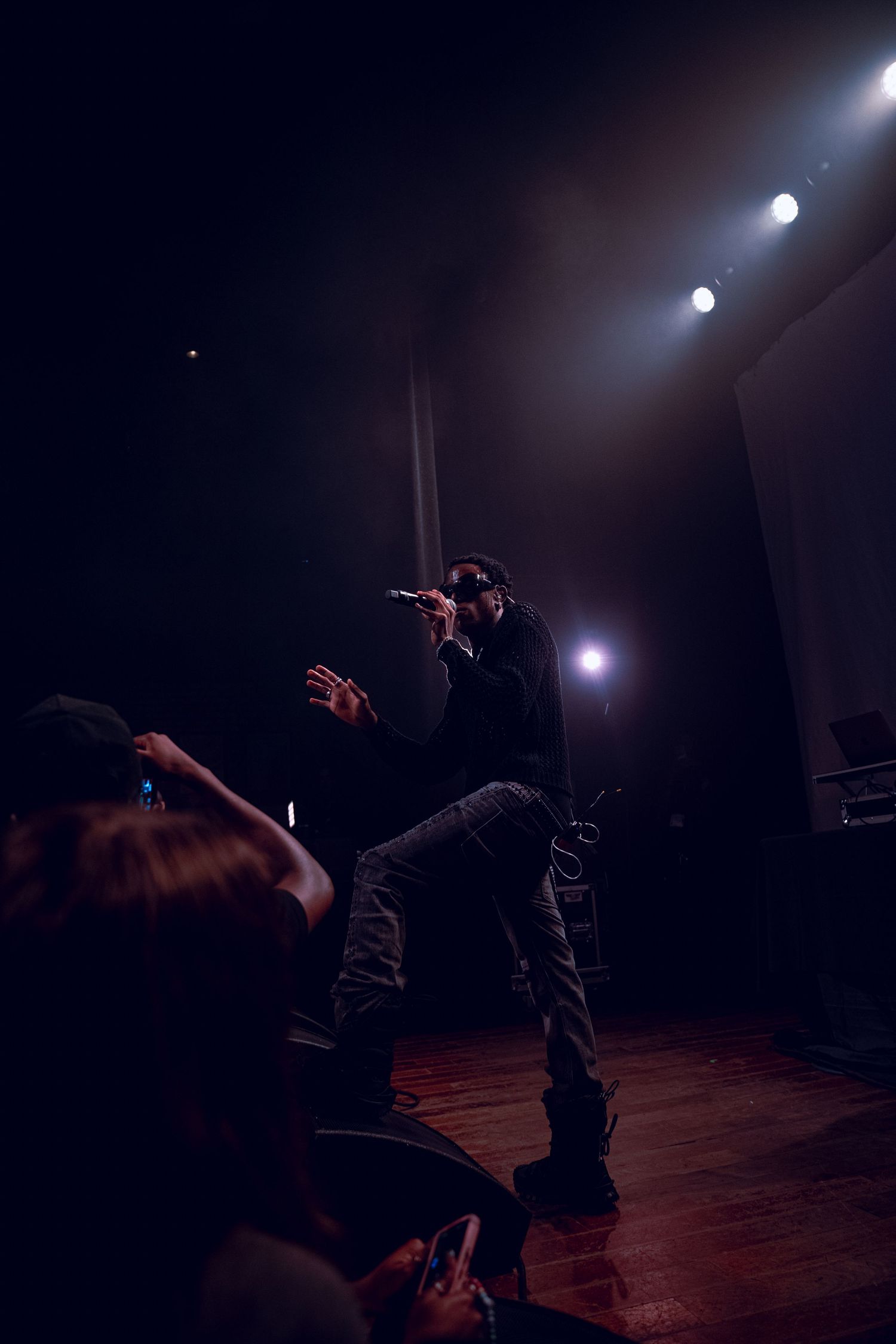 A silhouetted performer energetically moves on stage with dramatic backlighting.
