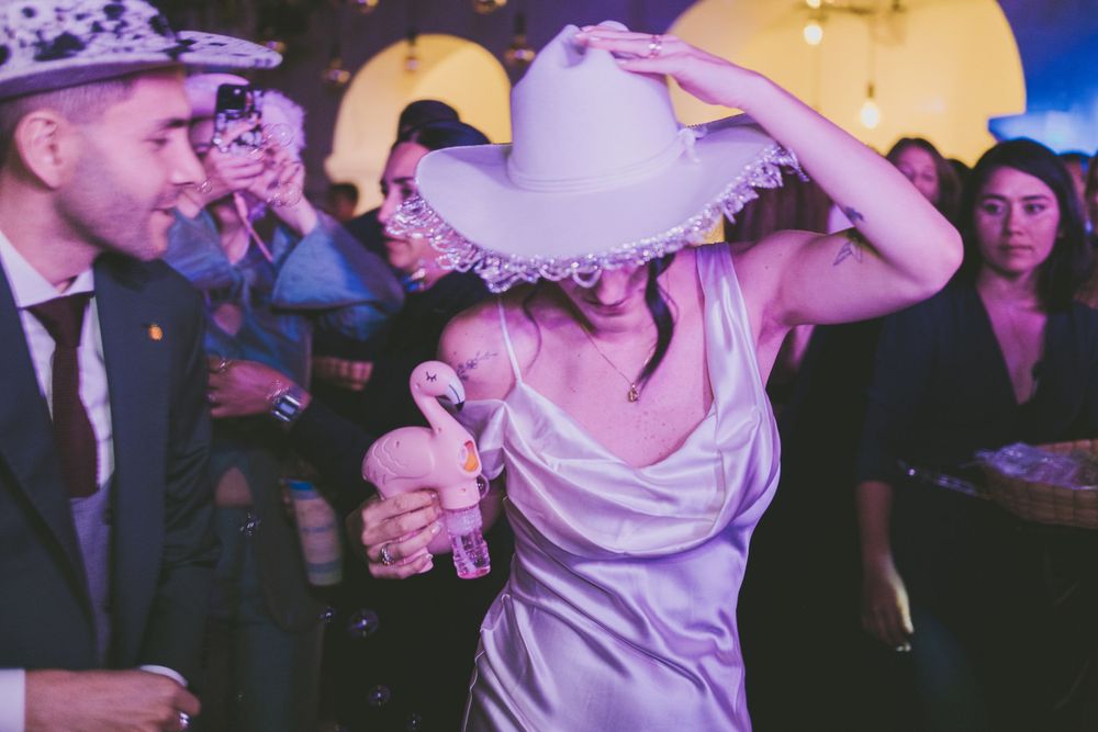 Bride wearing a cowboy hat during wedding party.