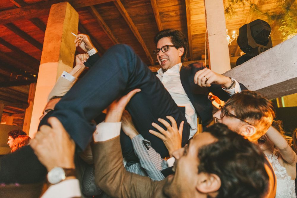 Groom is tossed in the air by friends to celebrate his wedding.