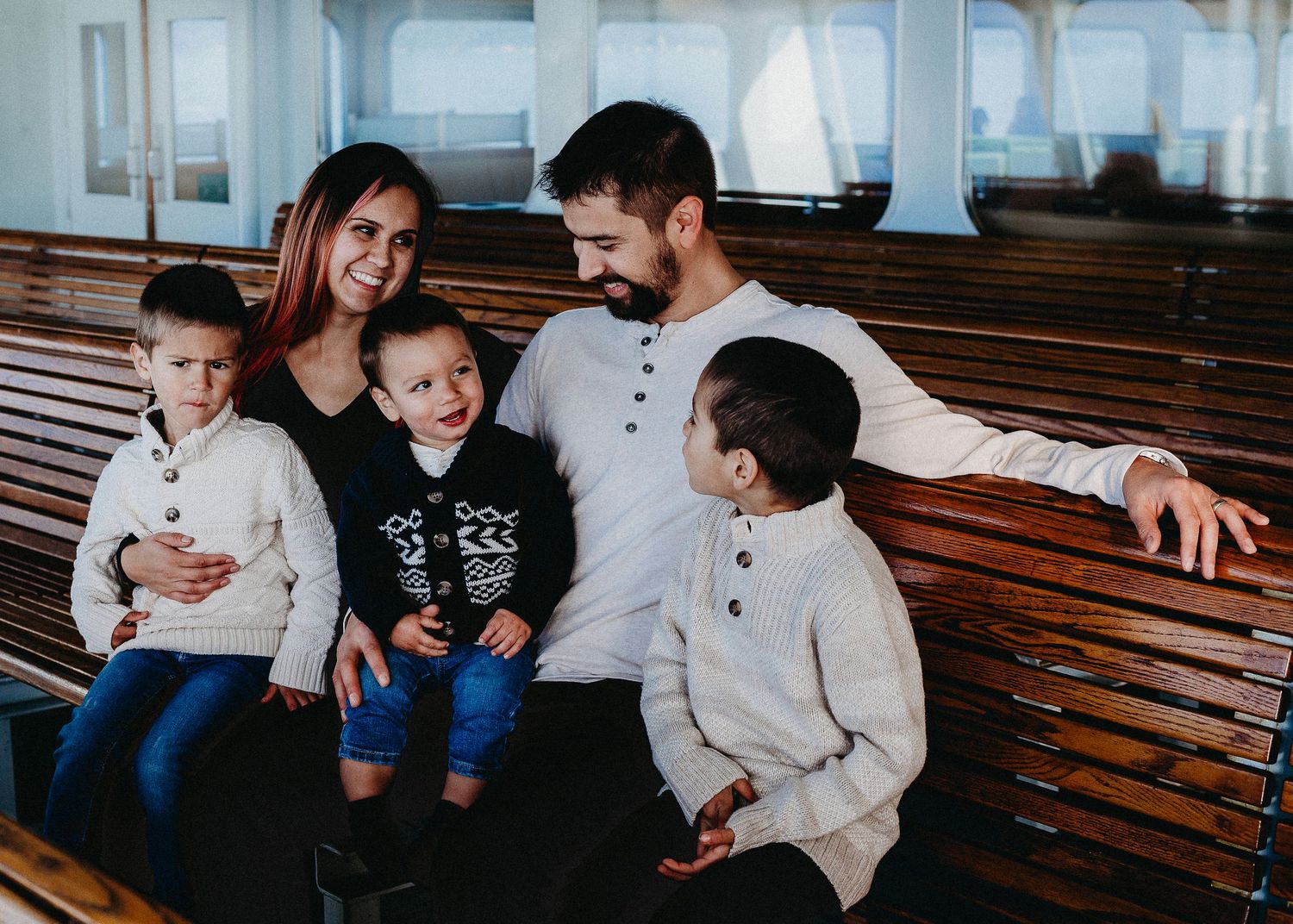 Family sharing a moment together while seated on wooden benches during a ferry ride.