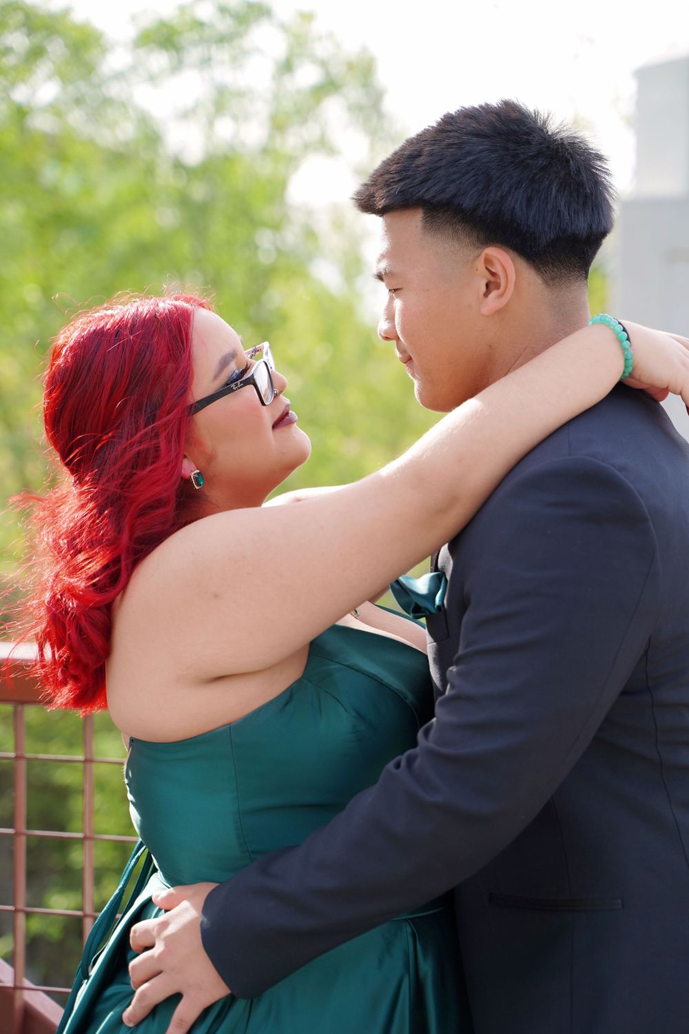 Intimate portrait of a couple in formal wear embracing on an outdoor platform.