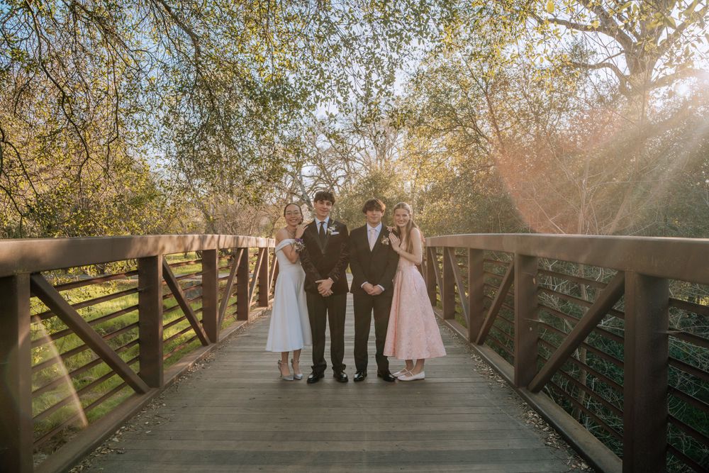 Scenic pathway with trees and people in formal wear gathered at golden hour.