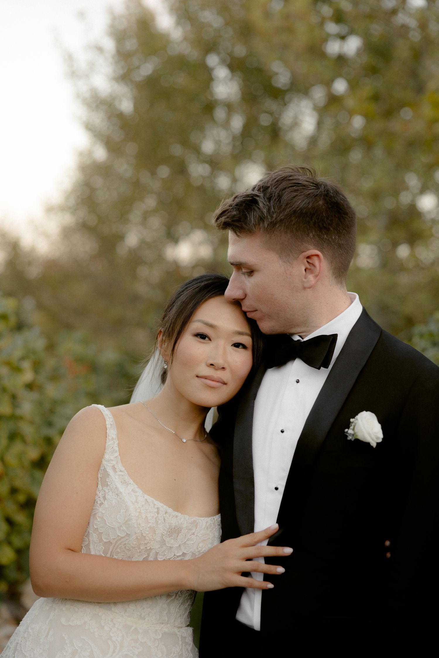A romantic wedding portrait of a couple in formal attire embracing outdoors with soft natural lighting. Pyrgos Petreza, Athens,
