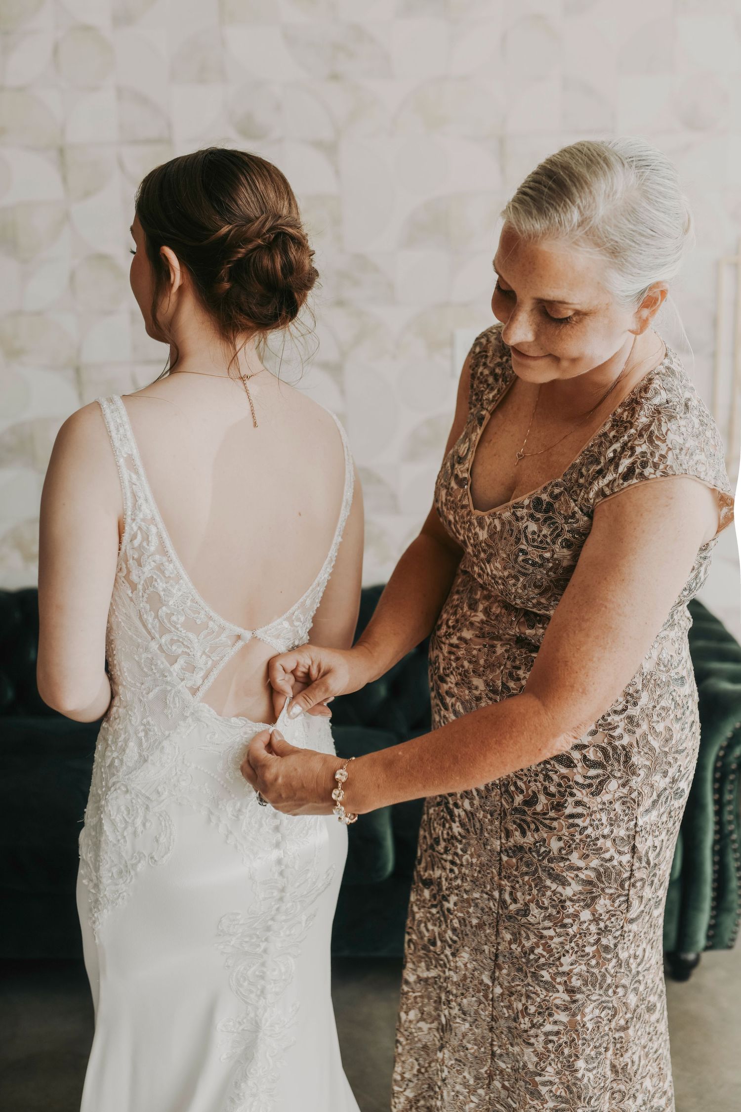 Bride and her mother buttoning the wedding gown during emotional bridal suite moment on wedding morning in Dallas.