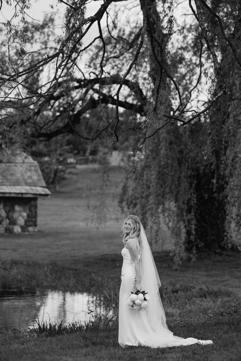 A black and white photo series showing a white dress near a weeping willow tree by a tranquil pond.