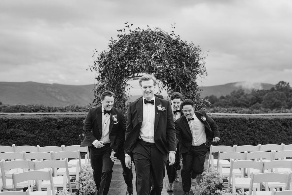 A black and white wedding photo montage showing outdoor ceremony moments and formal group poses under cloudy skies.