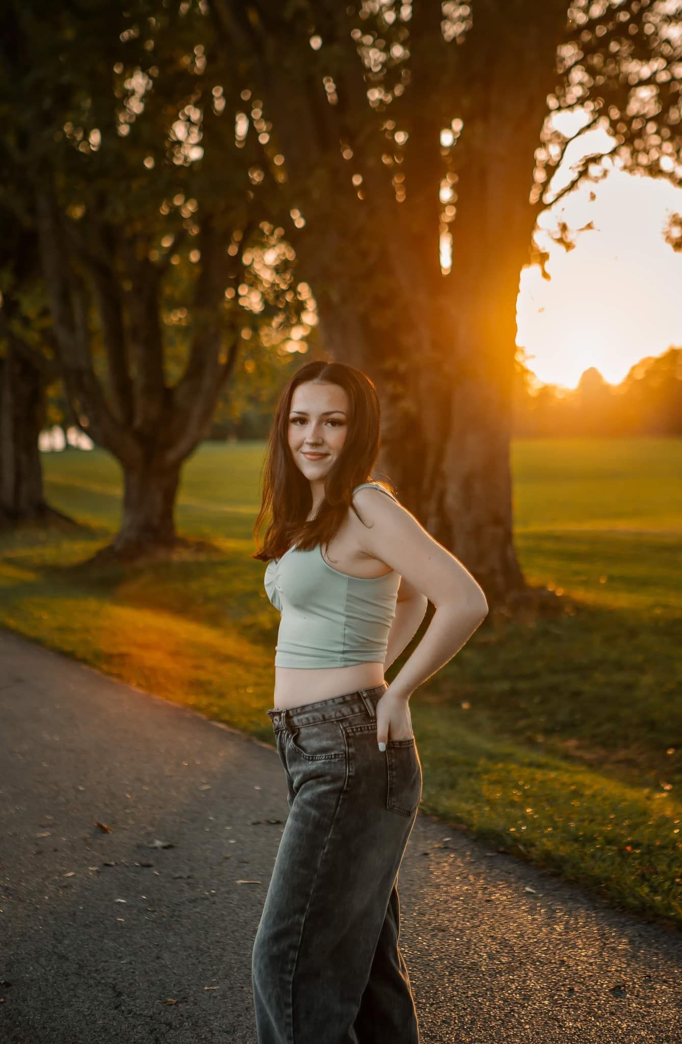 Golden hour portrait on park path wearing tank top and jeans.