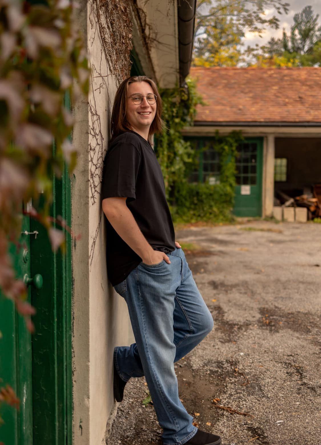 Casual portrait against rustic building wall with black shirt and jeans.