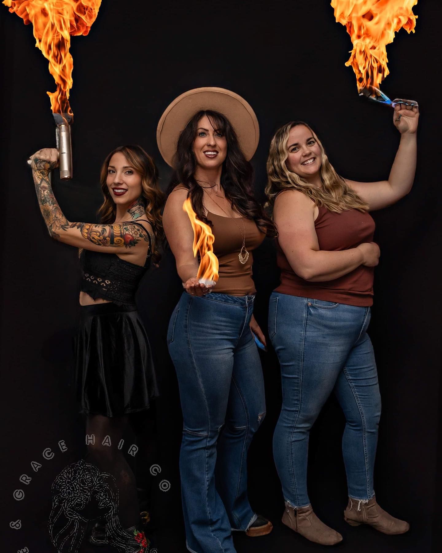 Three people posing with flaming torches against dark backdrop.
