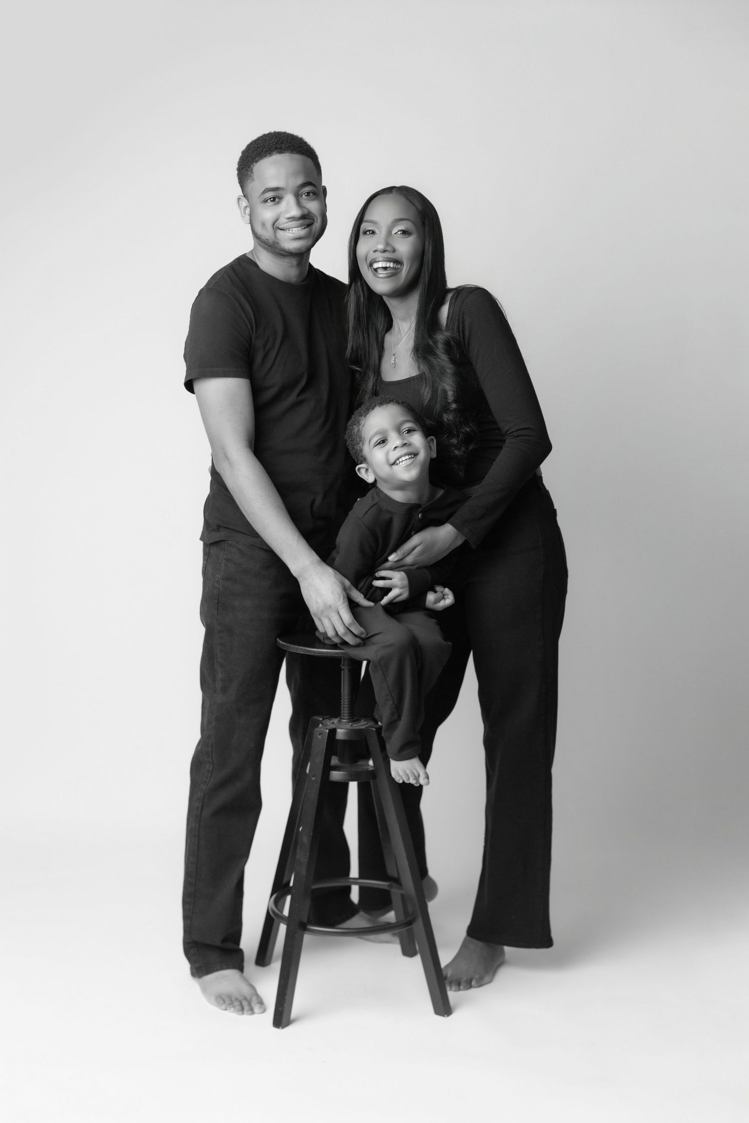 Black and white studio portrait series showing joyful family moments against a simple white backdrop.