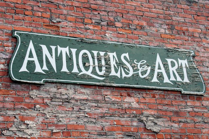 Vintage Antiques & Art sign mounted on a weathered red brick wall in St. Augustine, Florida.