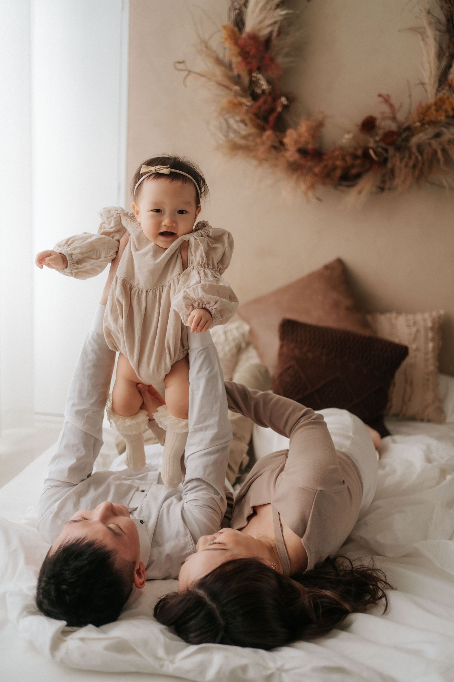 Two people in white clothing share intimate moments on a white bed with autumn decor in the background.