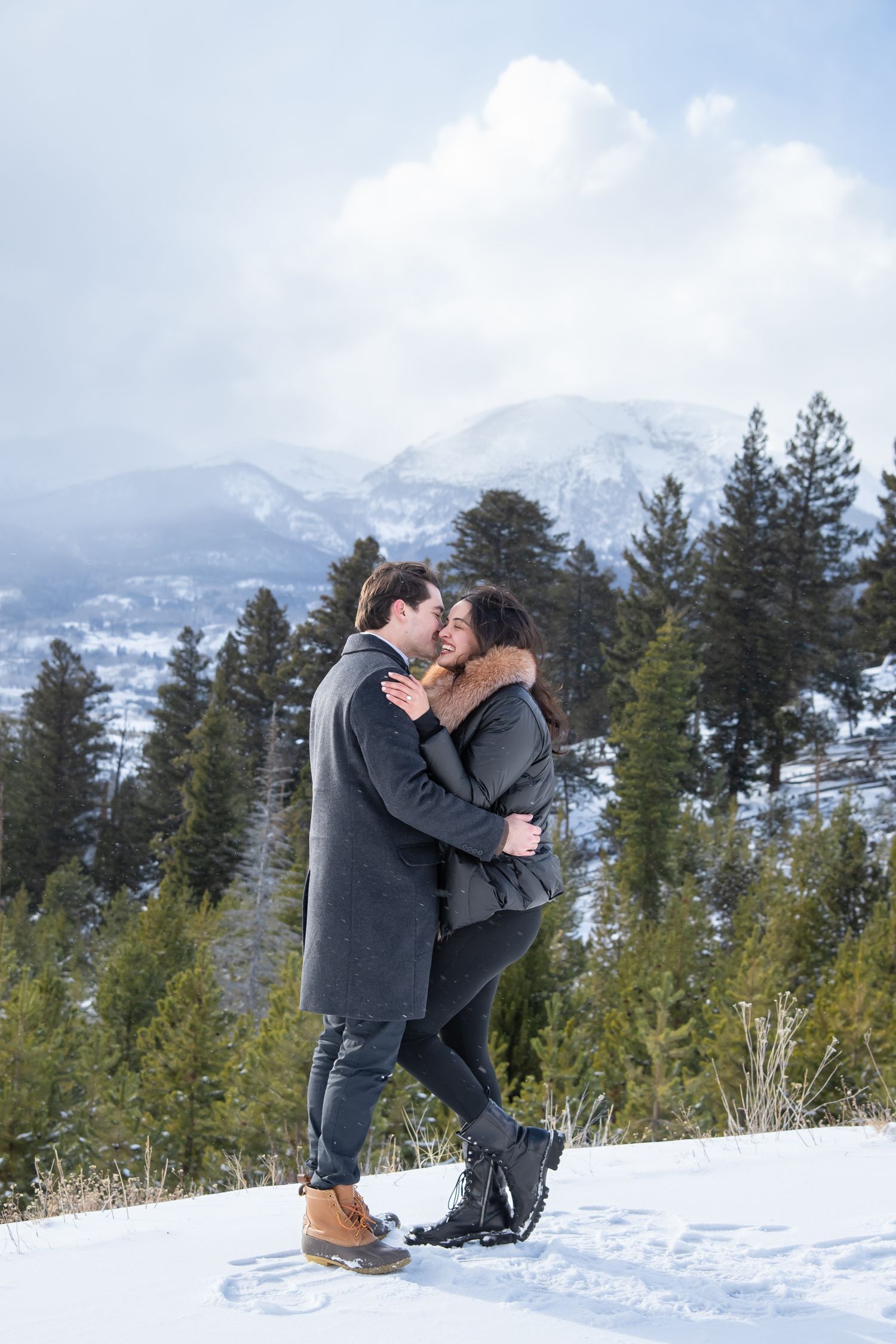 A romantic couple shares a tender moment with snow-capped mountains and evergreen trees in the background at Sapphire Point Colorado.