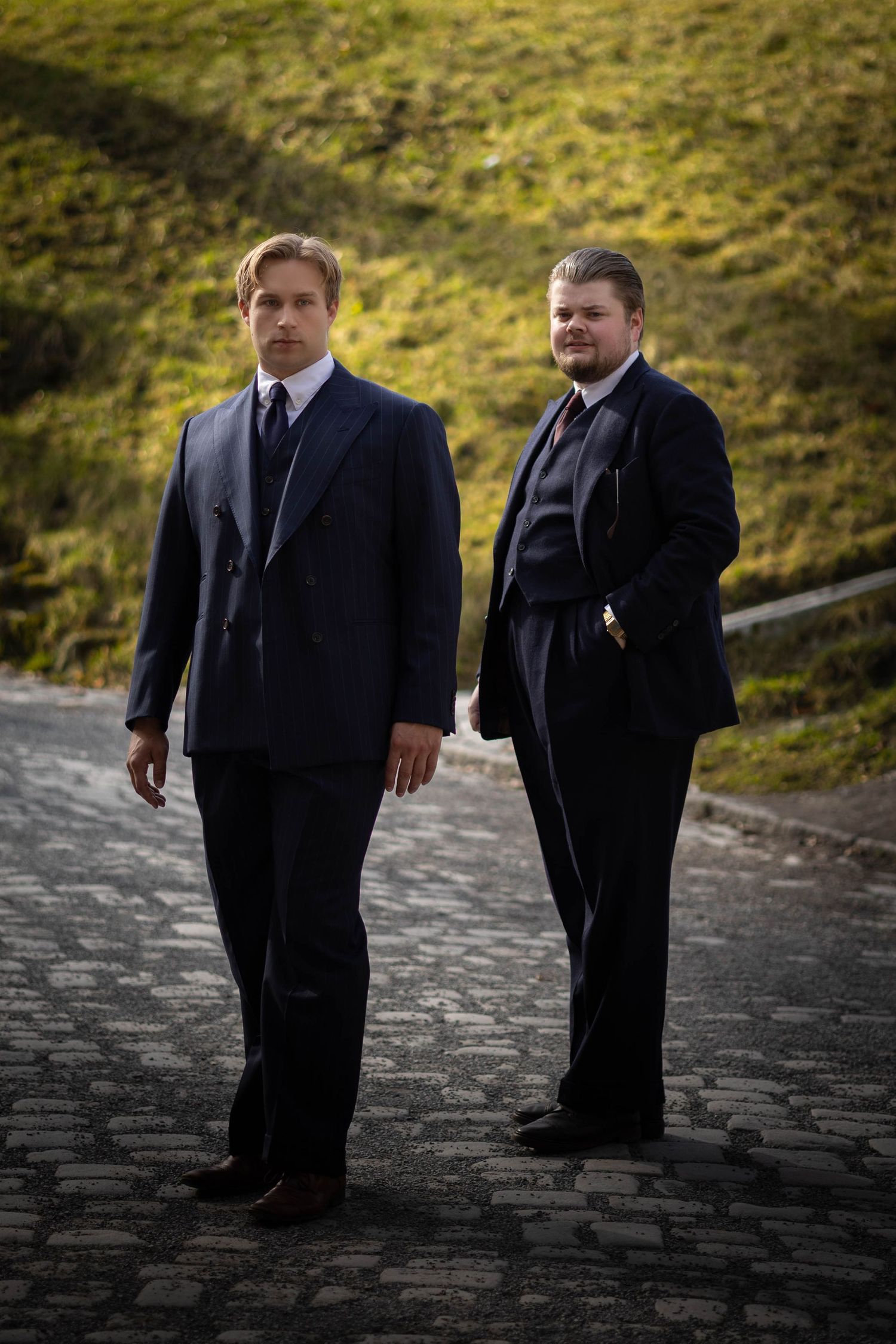 To menn i dress fotografert i skog, bryllupsfoto og groomsmen-portrett av Prospectxmedia.