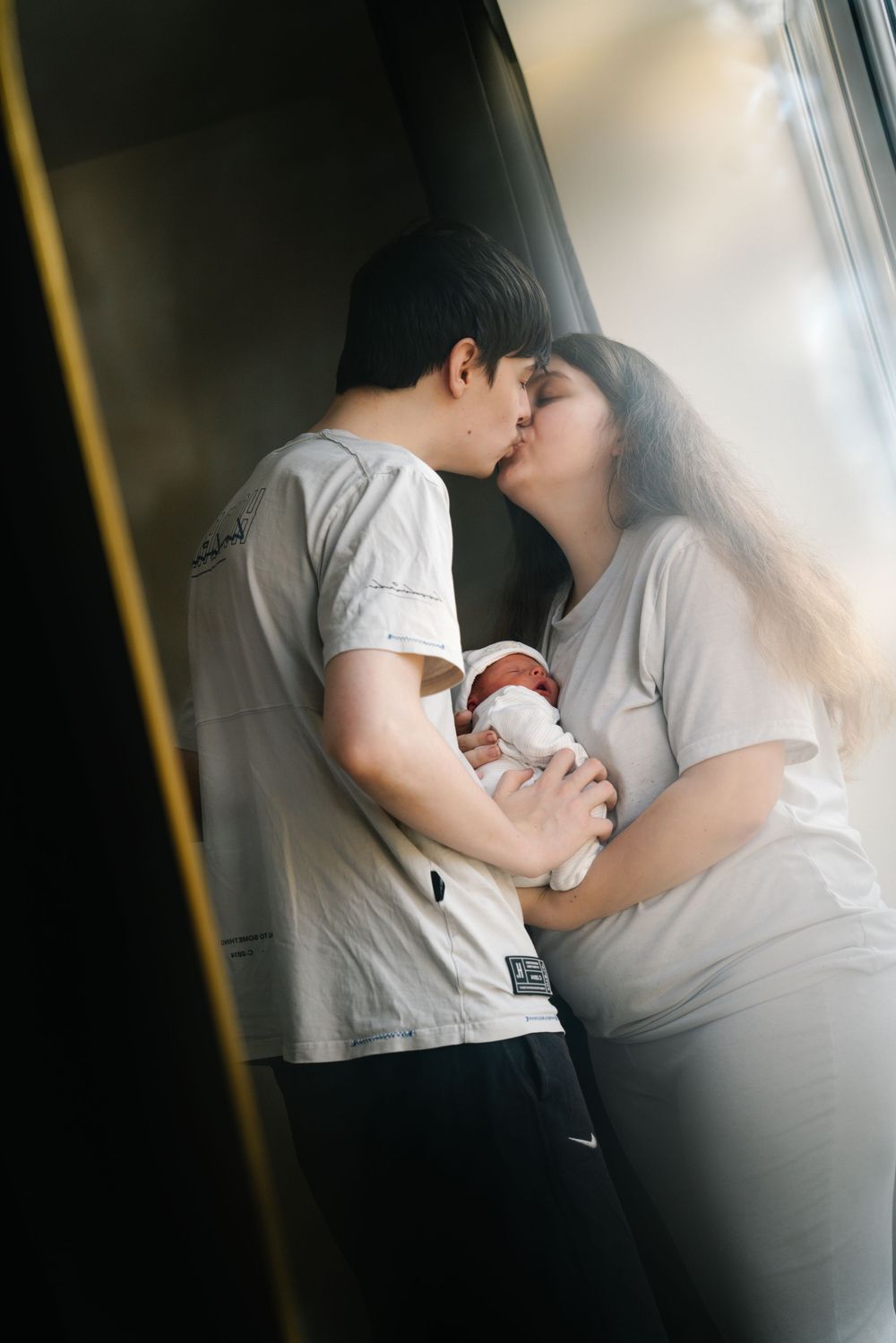 A tender moment captured in a series of intimate black and white photographs by a window.