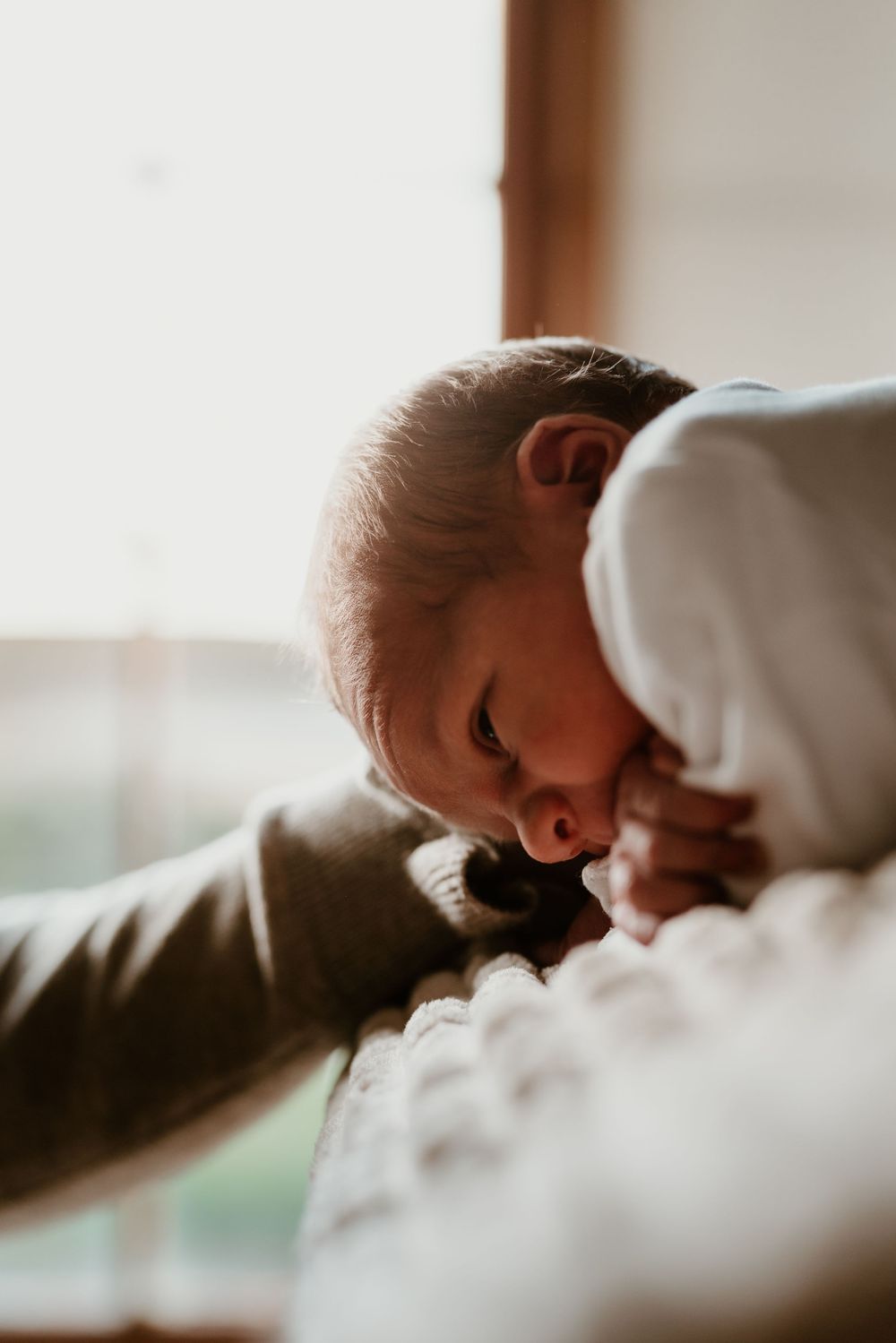 A tender close-up photo series showing a baby sleeping peacefully in white bedding.