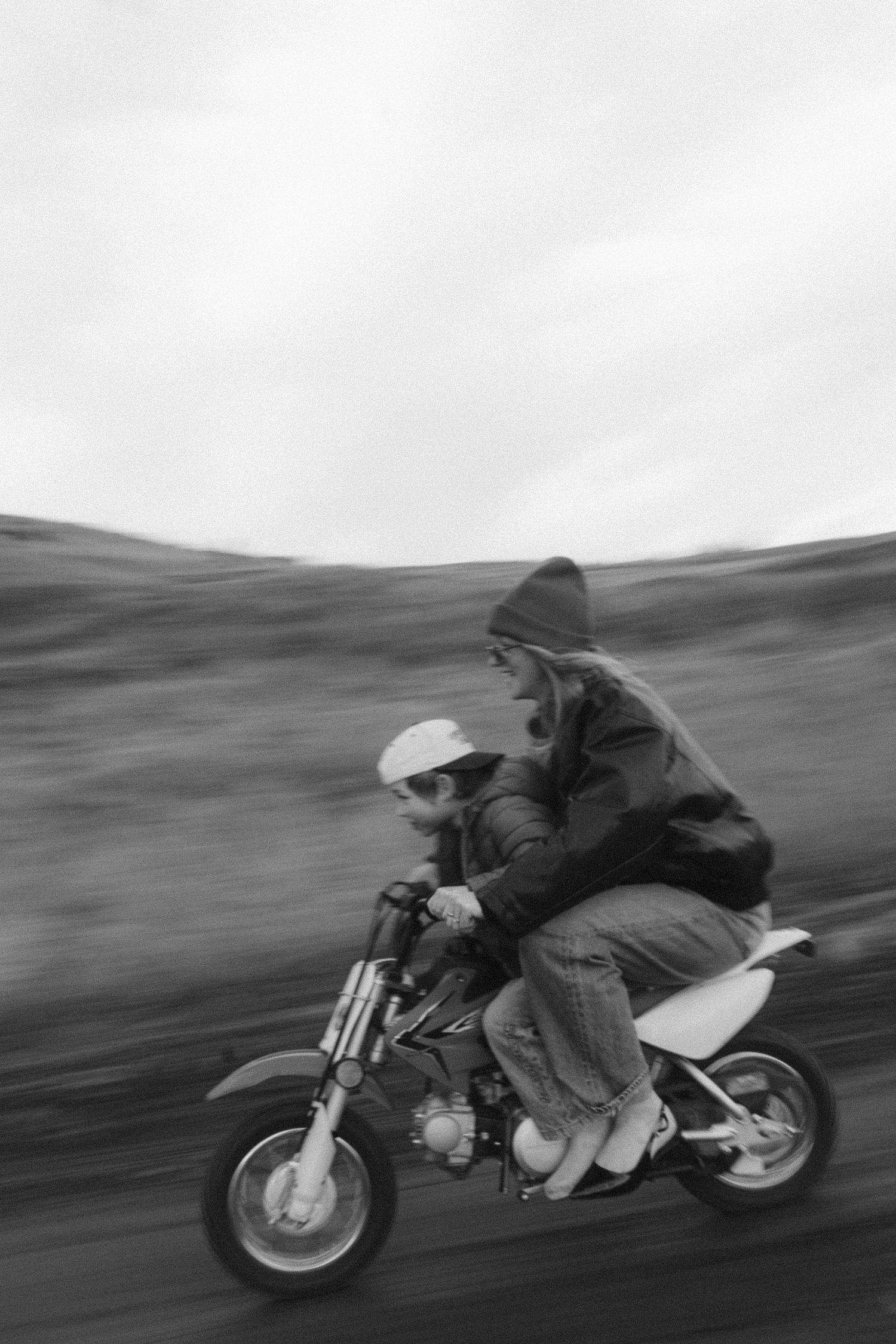 Black and white motion blur photograph of a motorcycle rider racing at high speed on a winding road.