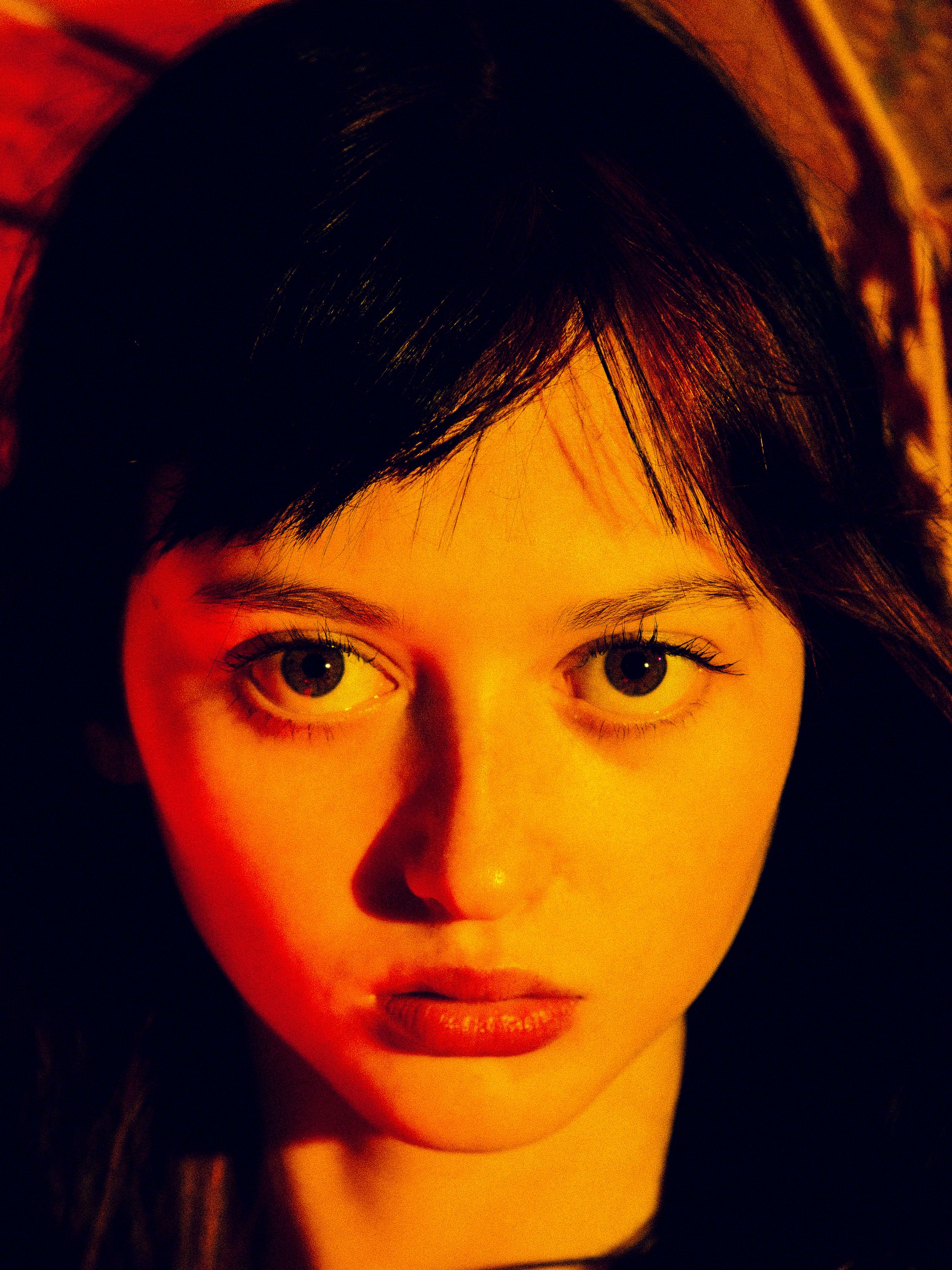 A series of close-up portraits in dramatic red and orange lighting creating a moody atmospheric effect.