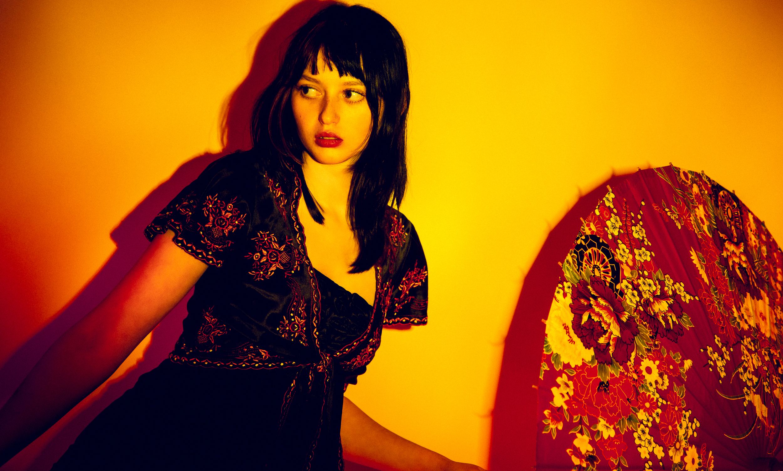 A dramatic fashion portrait series with orange lighting shows a model posing in traditional Asian-inspired clothing.